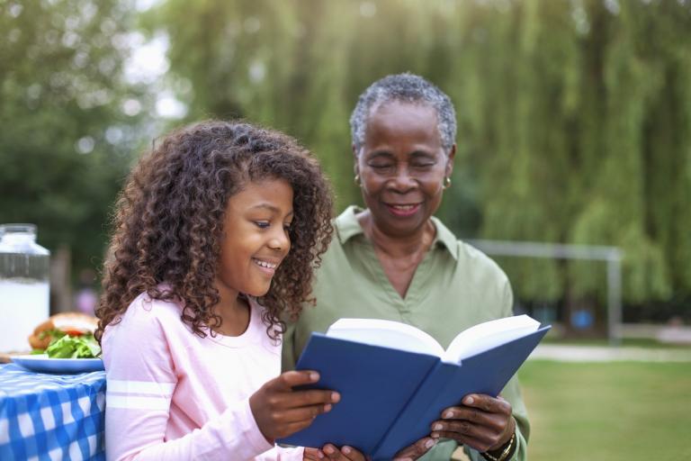 A grandmother reading with her granddaughter to avoid the summer slide.