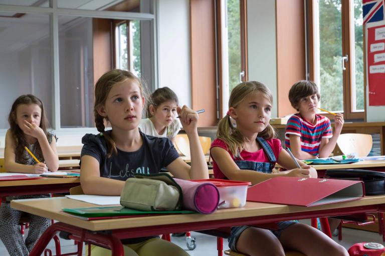 A group of young students in a small classroom environment.