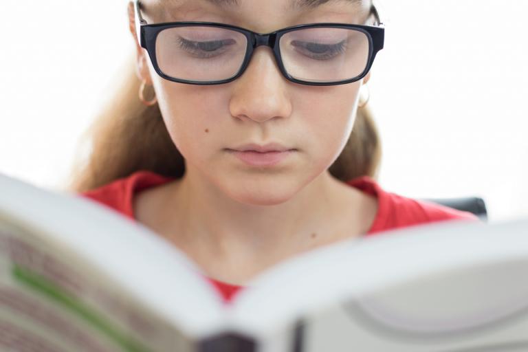 young female 2e student with learning disabilities reading a book in closeup on a white background