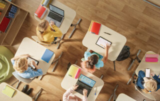 Group of students in a classroom using their laptops and tablets during their screen time.