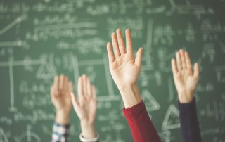 Students raised up hands green chalk board in classroom. Questions in Class