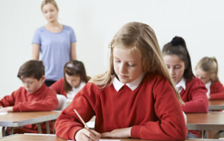 Group of students from private schools taking exam in a classroom.