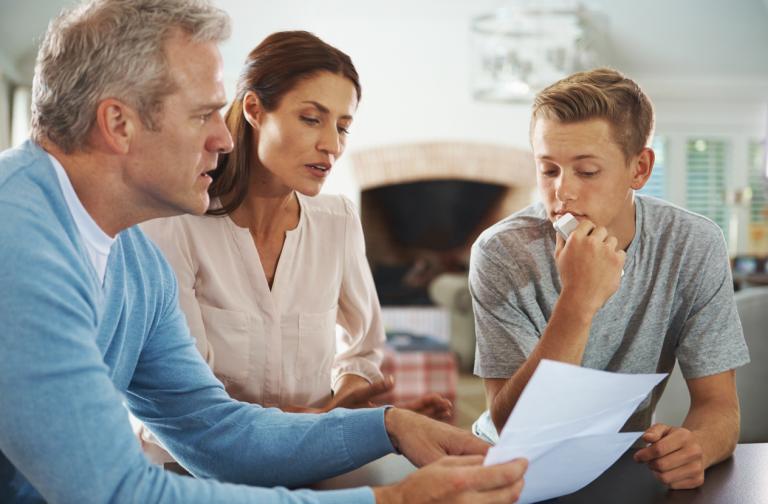 Parents with their son looking at his report card grades that are low