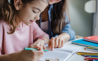 Mother engaged in student's educational experience helping her little daughter to study for school.