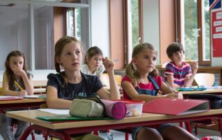 A group of young students in a small classroom environment.
