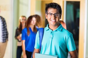 Friendly Indian high school student smiling in hallway