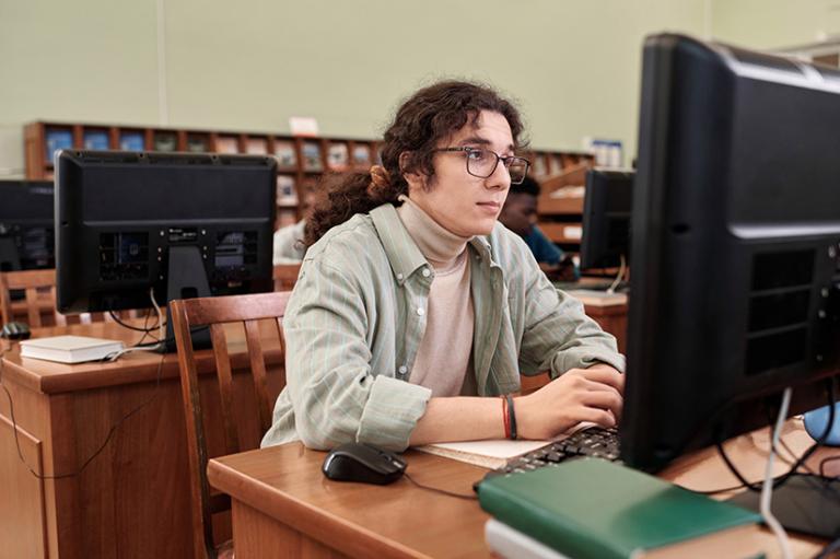 A student typing on a keyboard in a computer literacy classroom.