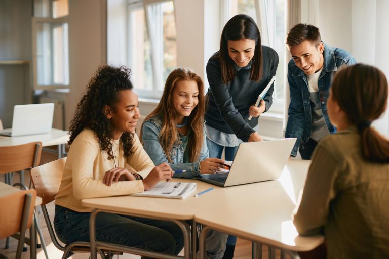 teacher-assisting-her-students-during-computer-class-in-a-classroom-achievement-gap-concept