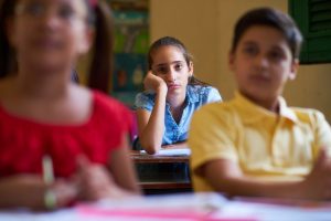 Young students in a traditional classroom. Group of hispanic students in class at school during lesson. Girl with anxiety, bored female student