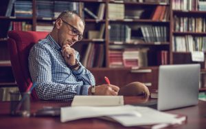 Teacher sitting at at desk in an office and writing a custom-made education plan