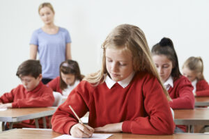 Group of students from private schools taking exam in a classroom.