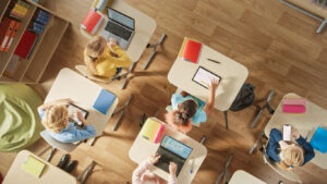 Group of students in a classroom using their laptops and tablets during their screen time.
