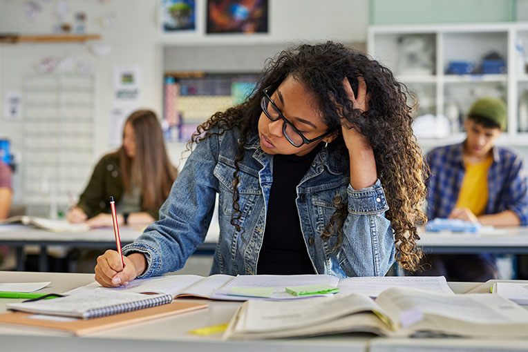 A tired student cramming before a big exam in a classroom.