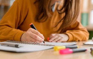 Young female student in class, taking notes and using highlighter. Get Ready for Final Exams concept.