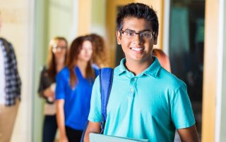 Friendly Indian high school student smiling in hallway