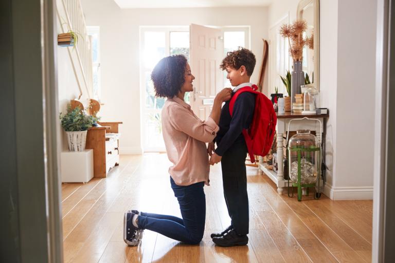 Mother At Home Getting Son Wearing Uniform Ready For First Day Of School. Transitioning to middle school concept