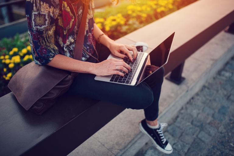 Teenager working from computer in the city park. Technology in school concept