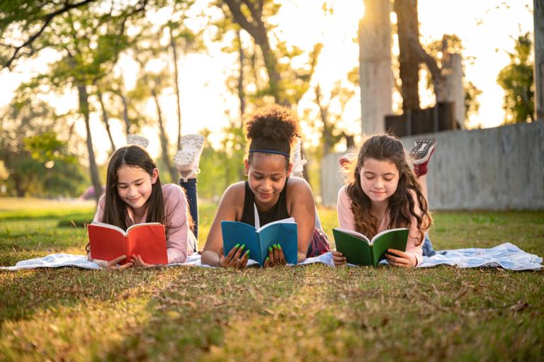 group-of-students-reading-books-in-the-school-park-summer-slide-concept