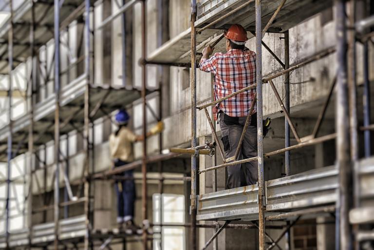 Back view of female and male worker on scaffolding.