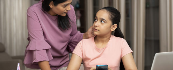 The mother is talking to her teenage daughter while the daughter is studying in her study area.