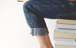 Gifted and talented student sits on a stack of books reading