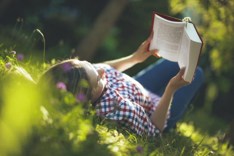 Teen outside in the summer reading in the garden