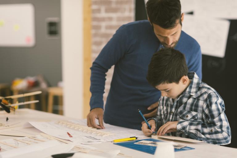 Gifted and Talented: Father and son making model of toy plane. Making a plane with small parts thay have and looking in plan on blueprits