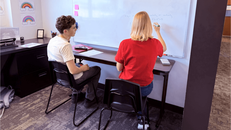 Tenney School teacher providing one-to-one math instruction at a whiteboard without a Chromebook.
