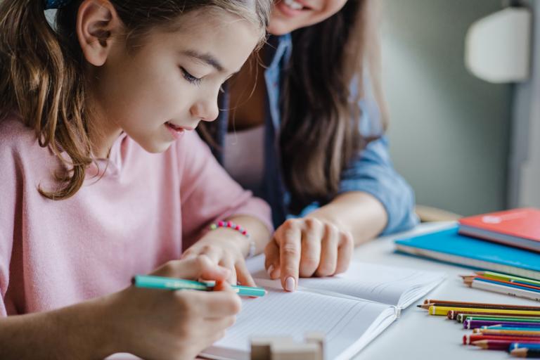 Mother engaged in student's educational experience helping her little daughter to study for school.