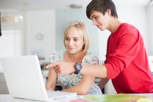 Mother and teenage son getting ready for school by using a laptop