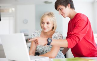 Mother and teenage son getting ready for school by using a laptop