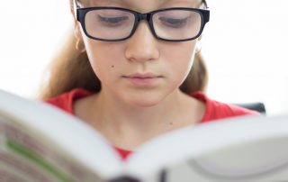 young female 2e student with learning disabilities reading a book in closeup on a white background