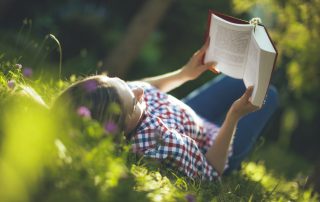 Teen outside in the summer reading in the garden