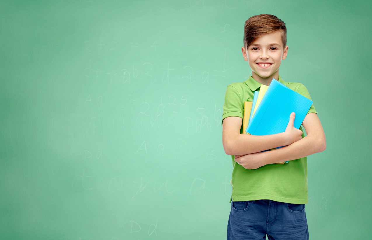 Gifted and talented boy student with folders and notebooks over green school chalk board background