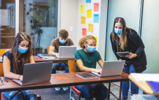 Students and a teacher wearing masks in a classroom in fall 2021.