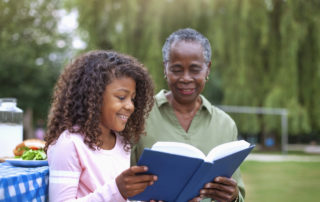 A grandmother reading with her granddaughter to avoid the summer slide.
