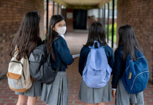 A middle school girl walking with her friends on the first day.