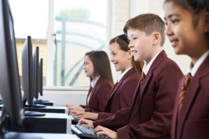 Students wearing school uniforms while using computers in a private school.