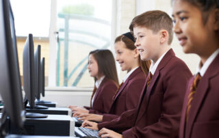 Students wearing school uniforms while using computers in a private school.