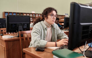 A student typing on a keyboard in a computer literacy classroom.