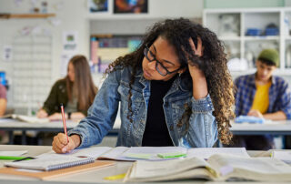 A tired student cramming before a big exam in a classroom.
